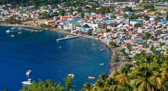 Aerial view of Soufriere, St. Lucia, showing colorful buildings along the coast and boats in the harbor.