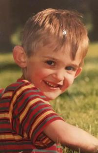 Photo of a smiling toddler in a striped shirt.