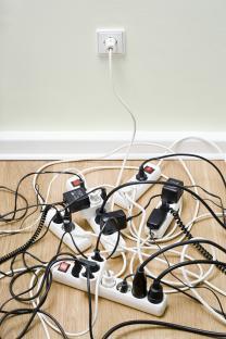 Tangled power cords and surge protectors on the floor.