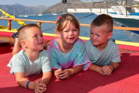Three young children lying on a boat deck.