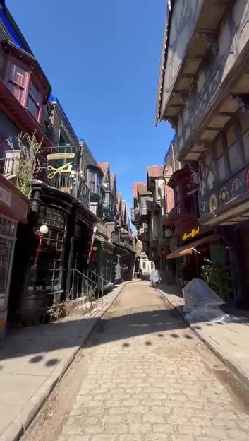 A cobblestone street featuring buildings of various heights and architectural designs, adorned with signs for fictional shops such as "Quality Quidditch Supplies" and "Accioffee," part of the new Diagon Alley set for the Harry Potter television series.