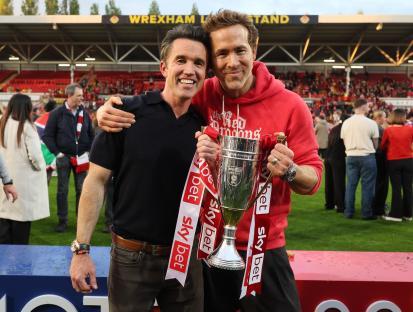 Rob McElhenney and Ryan Reynolds holding a trophy.