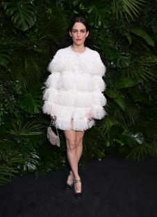 Riley Keough in a white feathered mini dress and silver shoes at a pre-Oscar party.