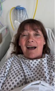 Lorraine Kelly in a hospital bed, speaking to the camera.