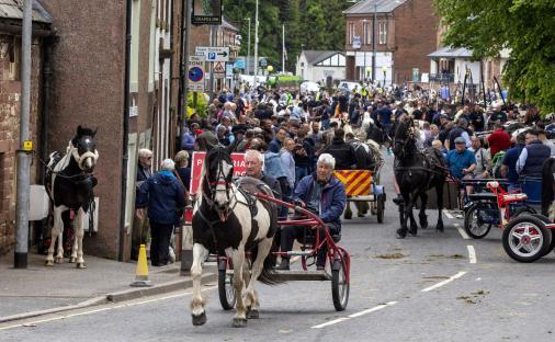 Horse-drawn carts and a crowd of people on a street.