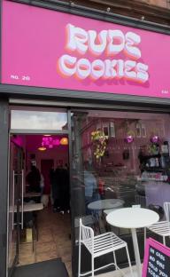the outside of rude cookies with tables and chairs