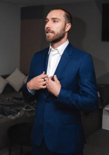 Man in a blue suit adjusting his jacket.