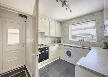 Kitchen with white cabinets, tiled backsplash, and appliances.