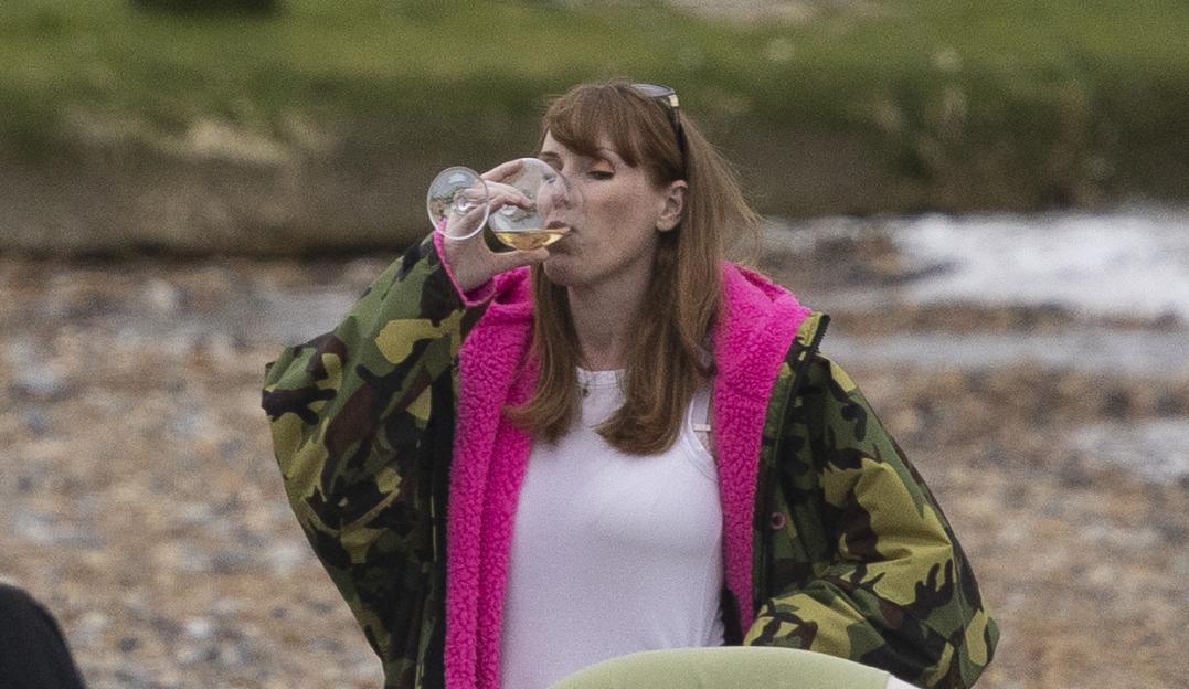 Angela Rayner drinking wine on a beach.
