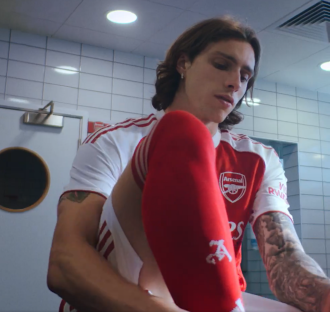 Arsenal soccer player putting on socks.