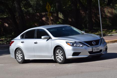 Silver Nissan Altima driving on a city street.