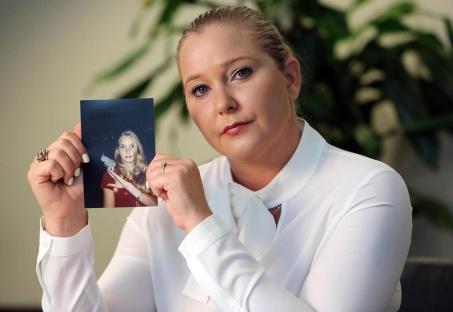 Virginia Giuffre holding a photo of herself as a teenager.