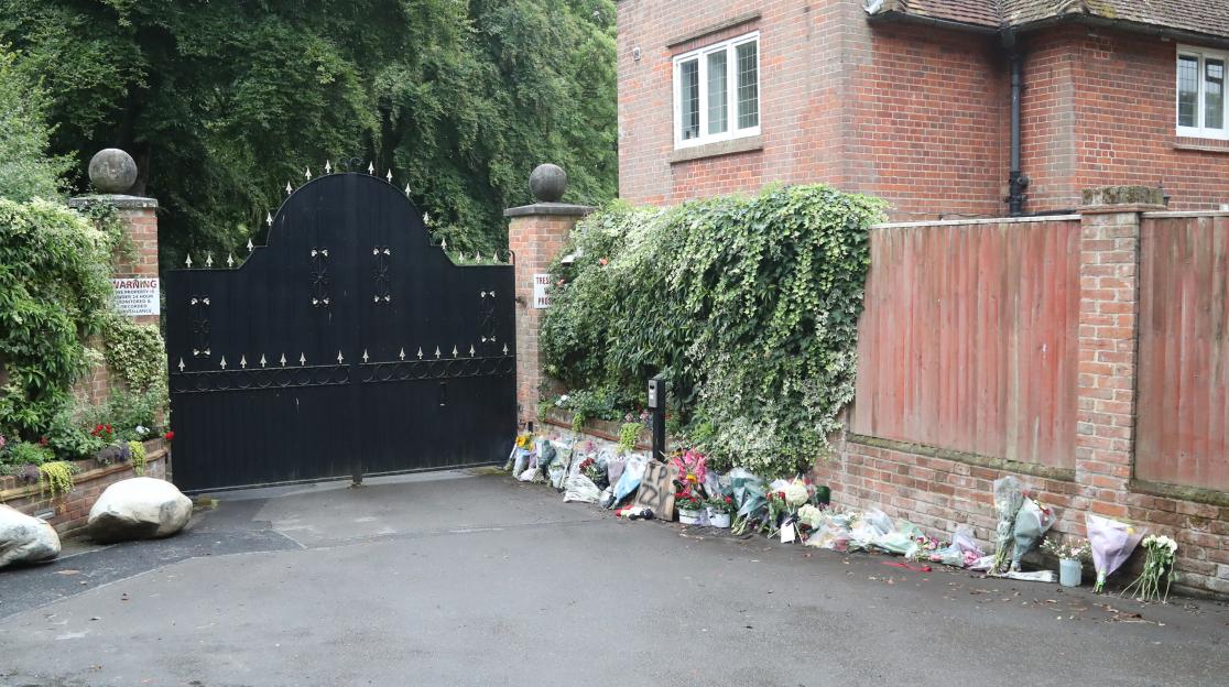 Floral tributes outside a gate.