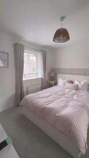 Bedroom with a pink gingham duvet on a white bed.