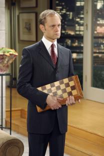 David Hyde Pierce as Dr. Niles Crane in Frasier, holding a chessboard.