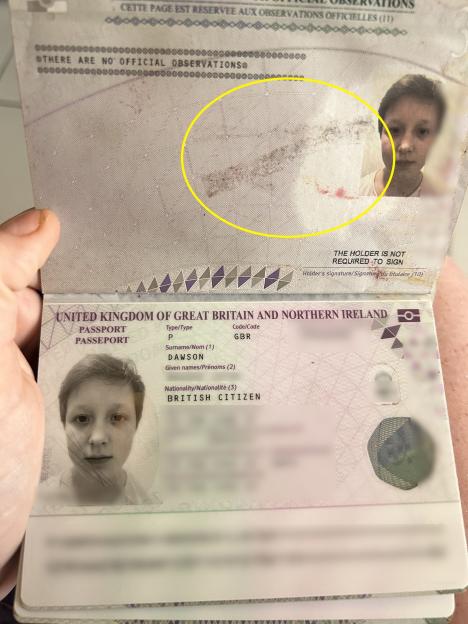 An open British passport, blurred for privacy, with a visible stain on the "Official Observations" page highlighted by a yellow oval.
