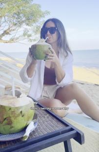 Woman drinking coconut water on a beach.