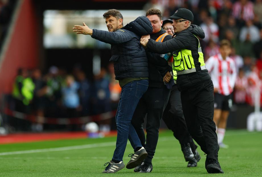 Soccer pitch invader being detained by stadium security.