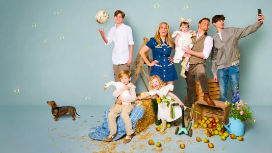 Family portrait with children, parents, and pets in a rustic setting.