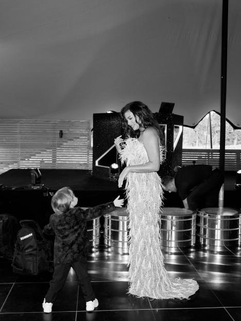 Jess Wright in a feathered gown smiling at a child reaching for her.