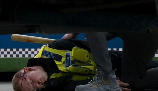 Injured police officer lying on the ground near a baseball bat.