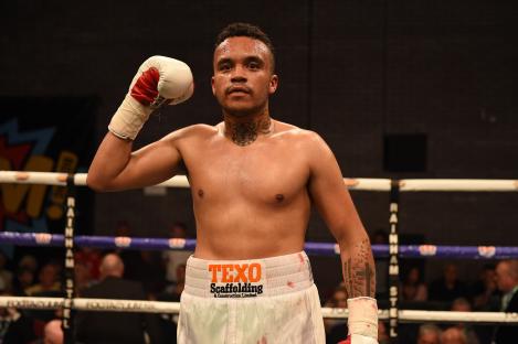 Boxer Harley Benn raises his arm in victory after a boxing match.