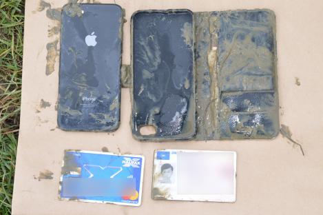 Mud-covered iPhone, bank card, and driver's license.