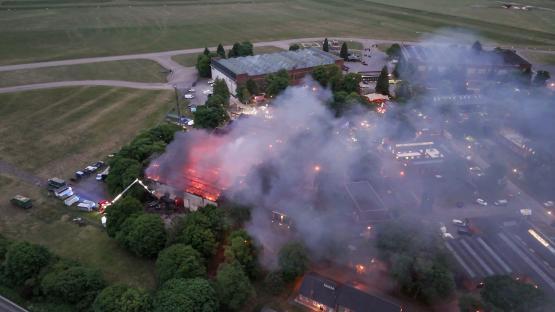 Aerial view of a large fire at a classic car restoration facility.