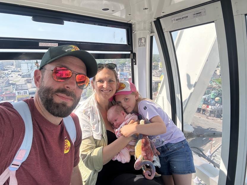 Family with newborn baby in Ferris wheel gondola.