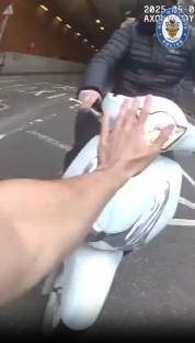 Screenshot of a hand stopping a white scooter in a tunnel.