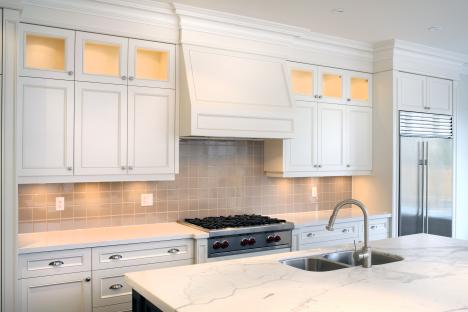 Luxury condo kitchen with white cabinets and marble countertops.