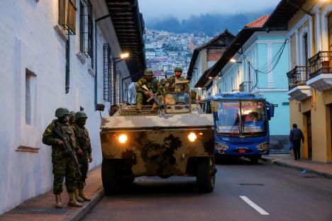 Soldiers patrol a city street in an armored vehicle.