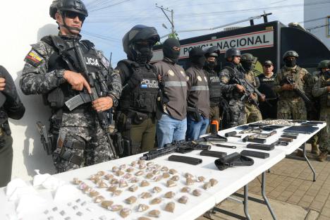 Police officers display seized drugs, weapons, and cell phones.