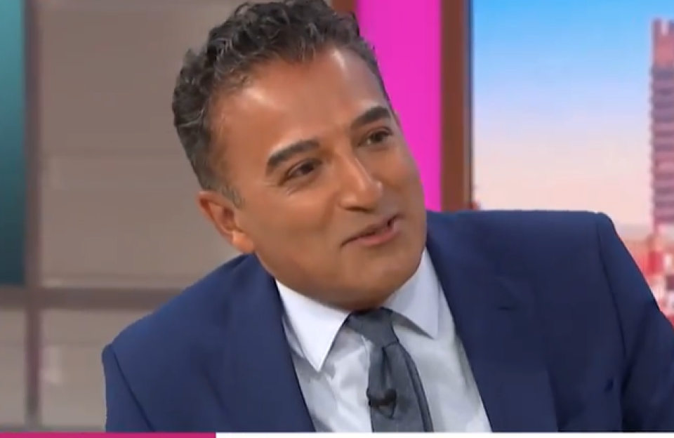 Adil Ray in a blue suit.