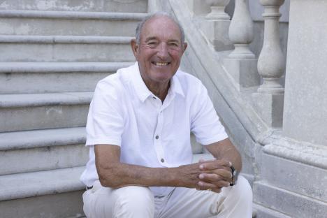 Smiling older man sitting on stone steps.