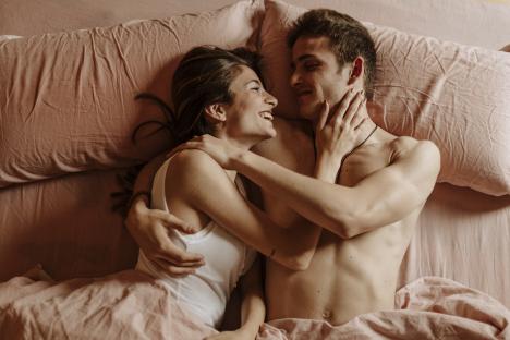 A young couple embracing in bed.