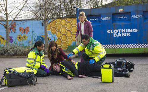 Paramedics attending to a bloodied injured man on the ground.