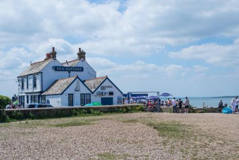 The Old Neptune, a beachside pub in Whitstable, England, with patrons enjoying food and drinks outside.