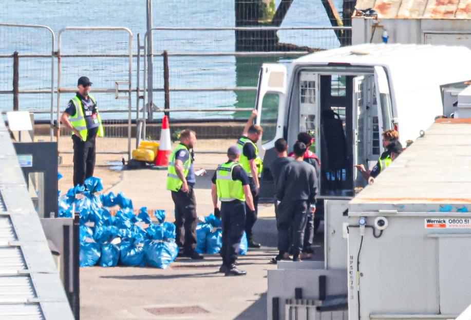 Four migrants being escorted to a van at the Port of Dover.