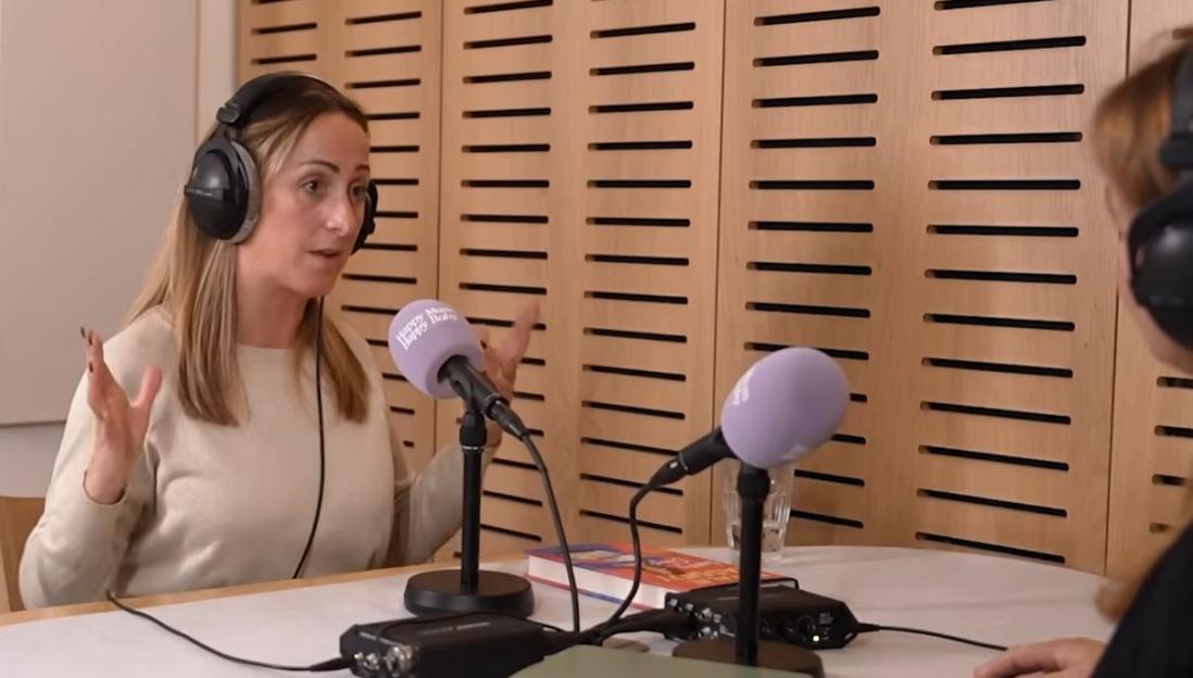 Natalie Cassidy wearing headphones and speaking into a microphone.
