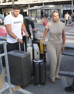 Molly Mae and Tommy Fury arriving at an airport with luggage.
