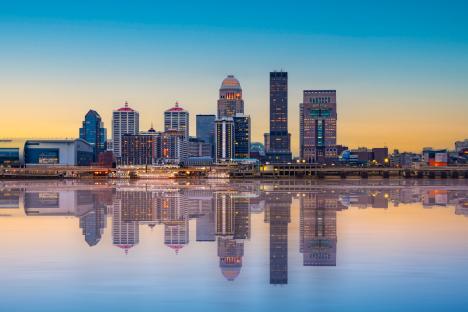 Louisville, Kentucky skyline at sunset reflected in the Ohio River.