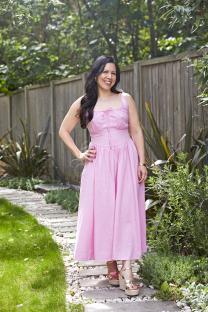 Woman in pink dress standing on a garden path.