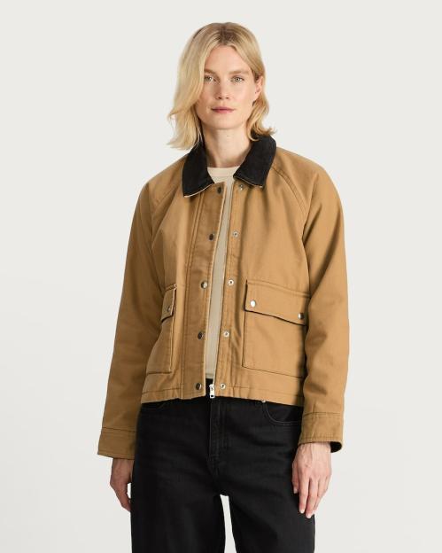 Woman modeling a tan jacket with a black collar.