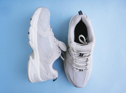 Pair of beige sneakers on a blue background.