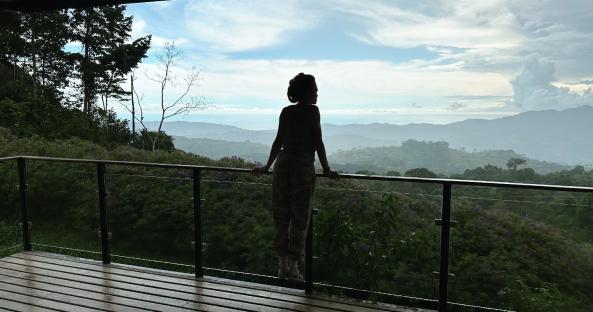 Silhouette of woman on balcony overlooking Costa Rican mountains.