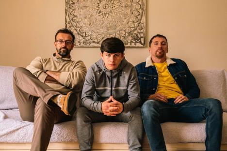 Three men sitting on a couch.