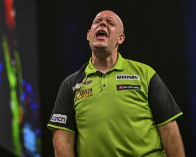 Michael van Gerwen grimacing during a darts match.