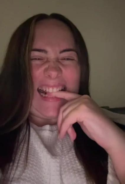 Woman smiling and touching her teeth.