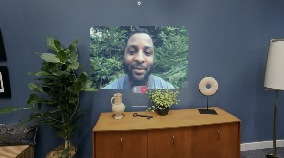 Video call displayed on a wall, with a man visible in the video.